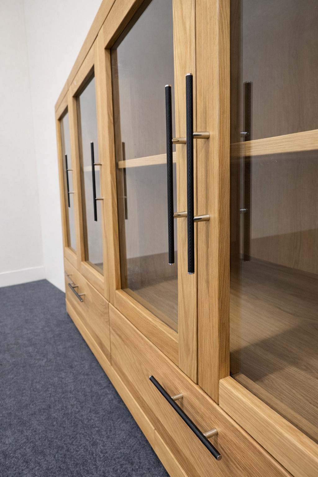 Ein moderner Holzschrank mit Glasfront und schwarzen Griffen, aus massivem Holz gefertigt.